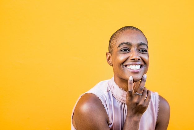 Primer plano y retrato de una joven y bella mujer afroamericana mirando a la cámara sonriendo y abriendo los ojos - alegre niña bonita disfrutando