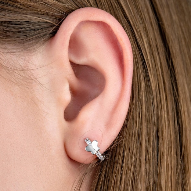 Primer plano retrato de joven hermosa morena modelo femenino presentando anillo y aretes de oro y plata Vista lateral de mujer en traje formal posando en estudio aislado sobre fondo blanco