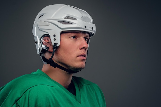 Primer plano retrato de jugador de hockey con un casco sobre fondo gris.