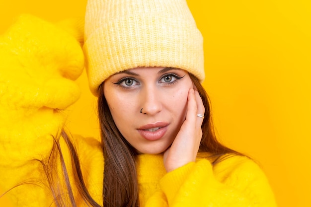 Primer plano retrato de mujer caucásica joven en suéter de lana aislado sobre fondo amarillo con gorra de lana