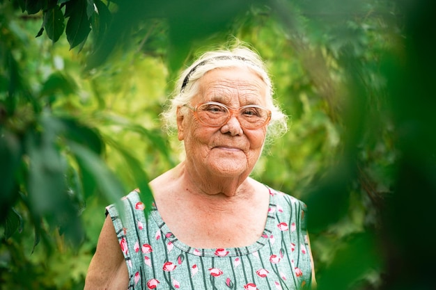 Primer plano retrato de una mujer mayor en un jardín Muy anciana de ochenta años con gafas