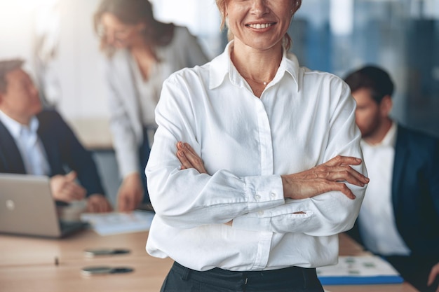 Primer plano del retrato de una mujer de negocios confiada mirando directamente con su equipo al fondo