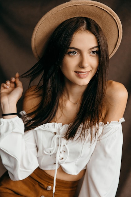 Primer plano retrato de niña adolescente feliz en sombrero sobre fondo marrón aislado