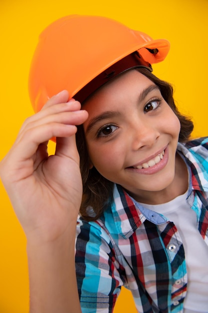 Primer plano retrato de niño constructor en casco Adolescente en trabajos de reparación aislado sobre fondo amarillo Concepto de renovación de niños