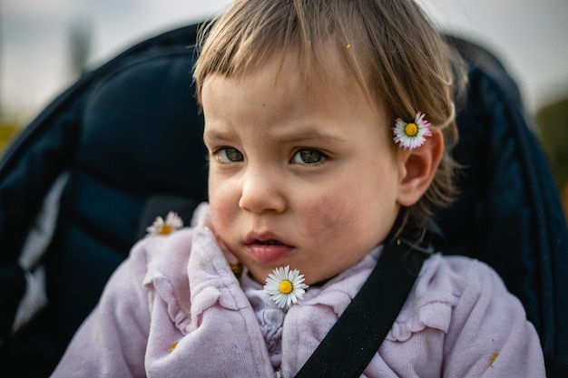 Primer plano retrato de niño pequeño con pelo blod y flores pequeñas