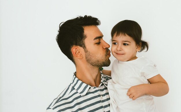 Primer plano retrato de padre guapo besar a su pequeña hija Padre joven abrazando a su hijo Hombre atractivo jugar con niña pequeña Padre feliz e hija Familia de estilo de vida