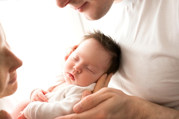 Primer plano retrato de padres jóvenes y bebé recién nacido Padre y madre besan y abrazan a una hermosa hija recién nacida El concepto de amor feliz paternidad y maternidad Fotografía sobre fondo blanco