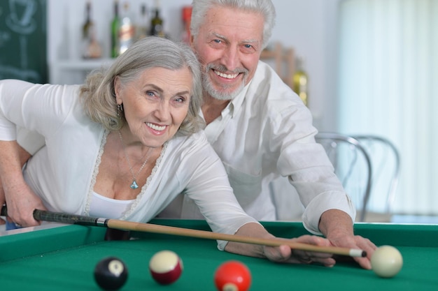 Primer plano retrato de una pareja senior sonriente jugando al billar juntos