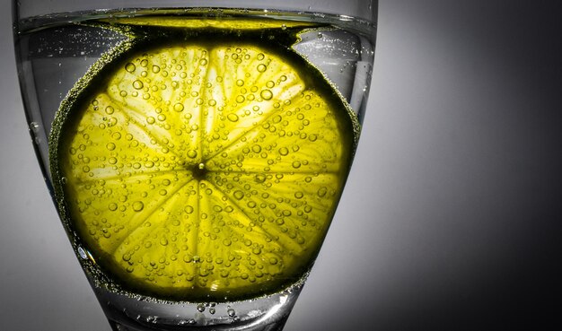 Foto primer plano de una rodaja de cal en agua carbonatada contra un fondo gris