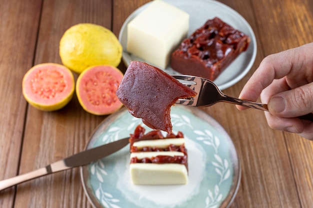 Primer plano de una rodaja de guayaba dulce con un bocado En el fondo requesón y dulce de guayaba en un bar