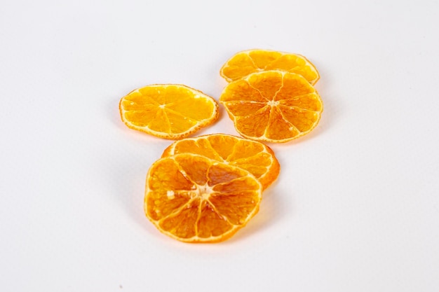 Primer plano de rodajas de naranja seca sobre fondo blanco.