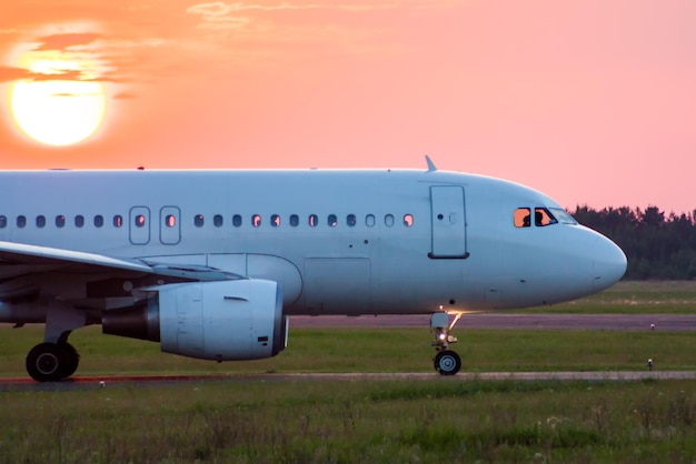 Primer plano de rodaje de un avión de pasajeros blanco contra el sol poniente