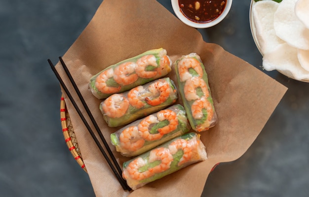 Primer plano de rollitos de primavera vietnamitas con pollo tierno langostinos chips de arroz sobre un fondo gris salsa de sésamo