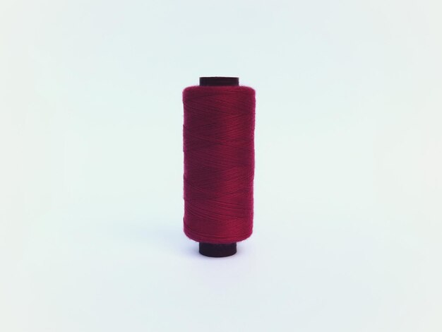 Primer plano de un rollo de hilo de coser rojo en posición de pie