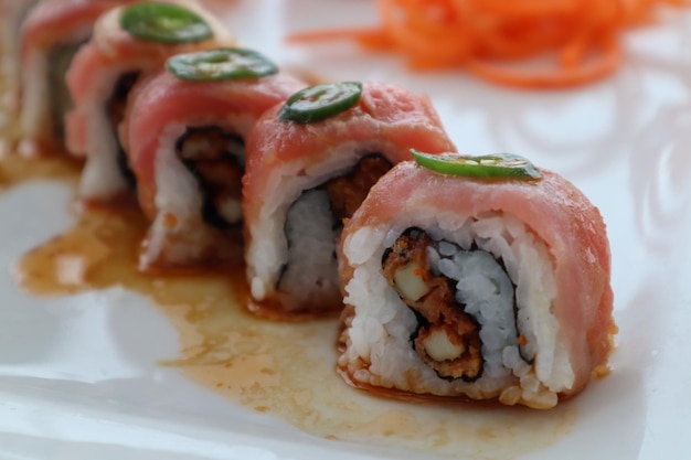 Primer plano de rollo de sushi con guarnición de jalapeño y zanahorias ralladas en un resort de lujo