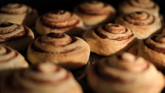 Primer plano de rollos de canela recién horneados en el horno remolinos marrones dorados de masa y canela