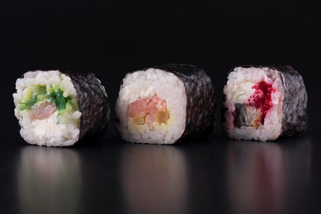 Primer plano de rollos de sushi con salmón y caviar sobre fondo negro