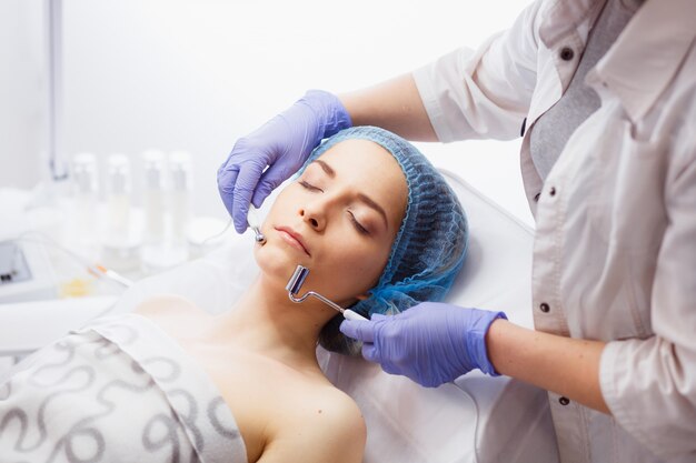 Primer plano del rostro femenino joven durante la terapia de microcorriente.