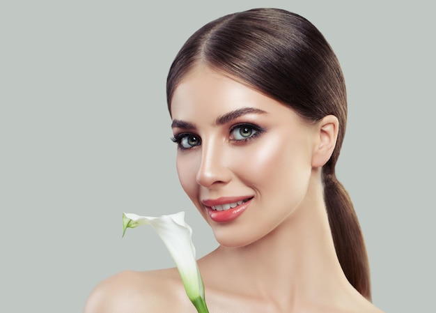 Primer plano de rostro femenino Spa Hermosa mujer con piel sana y flor de cala blanca