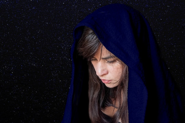 Primer plano del rostro de una mujer en un chal azul oscuro, sufrimiento, tristeza, tristeza. El concepto de tragedia o tristeza.