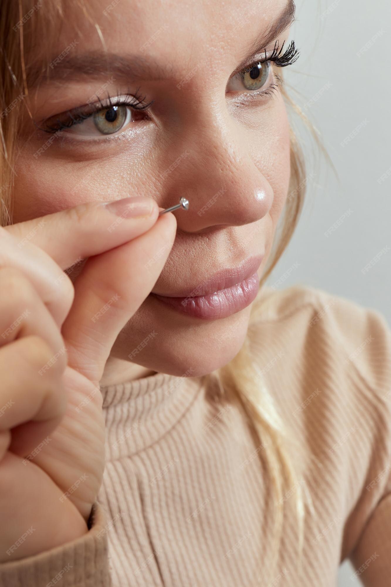 Primer plano de un rostro de mujer joven con piercing colgando de su nariz  | Foto Premium