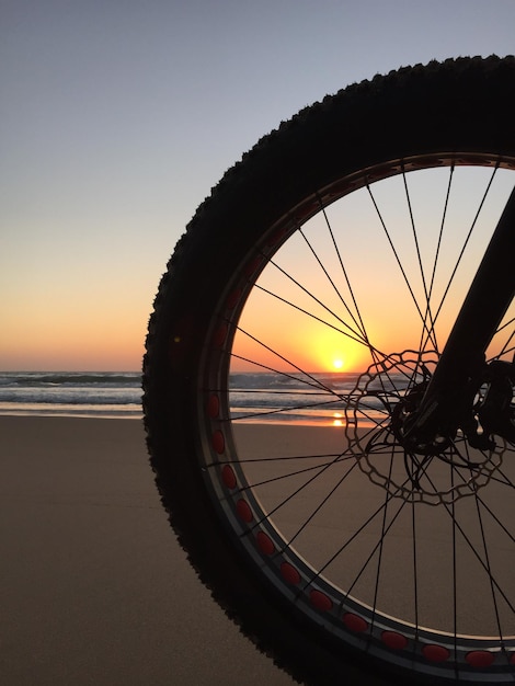 Foto primer plano de una rueda de bicicleta en la playa contra un cielo despejado