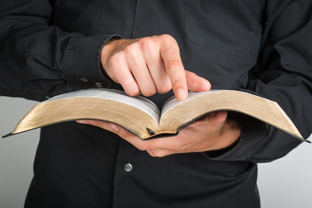 Primer plano de un sacerdote sosteniendo una Biblia y señalar con el dedo