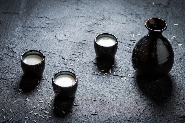 Primer plano de sake en cerámica negra sobre roca negra