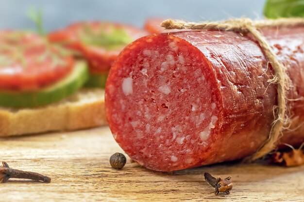 Primer plano de la salchicha de salami en el tablero de madera de corte, alimentos grasos nocivos