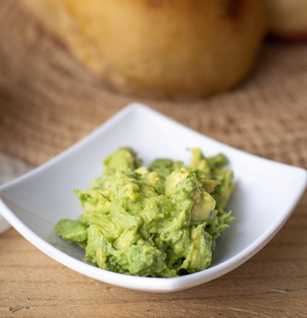 Foto primer plano de salsa de guacamole en un tazón sobre fondo amarillo con espacio de texto libre propagación de aguacate saludable