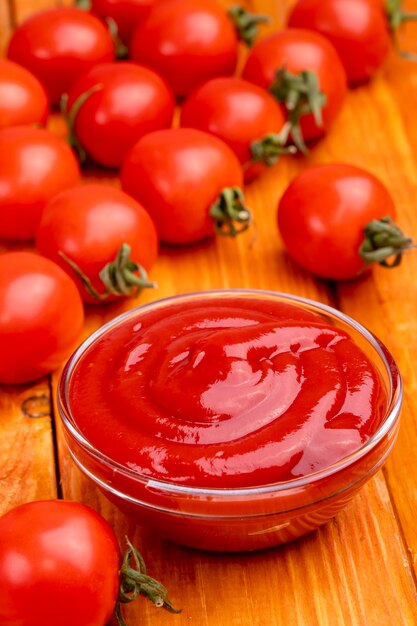 Primer plano de salsa de tomate y tomates sobre un fondo de madera