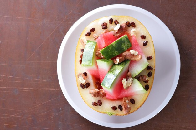 Primer plano de sandía y melón delicioso y saludable Rebanadas maduras de sandía y melón en un plato blanco sobre un fondo oscuro