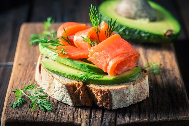 Primer plano de un sándwich con aguacate, salmón y eneldo