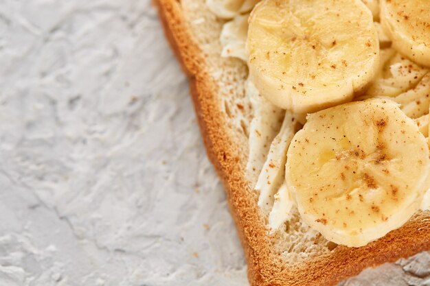 Primer plano de un sándwich dulce con queso y plátano sobre un fondo de textura gris