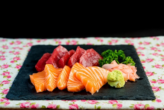 Primer plano de sashimi en pizarra en la mesa contra un fondo negro
