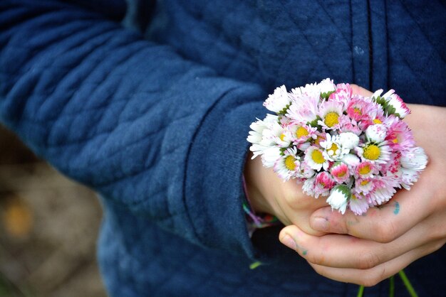 Foto primer plano de la sección media de las manos sosteniendo flores
