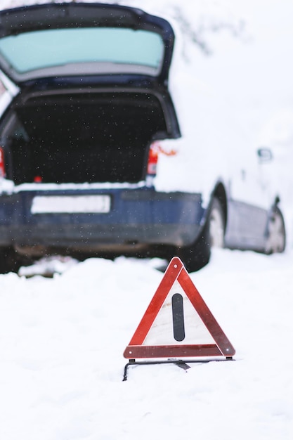 Foto primer plano de una señal de tráfico en la nieve contra un coche