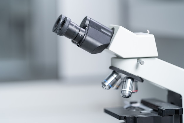 Primer plano y sesión de enfoque selectivo de un microscopio, tubos de ensayo médicos con líquido y otros equipos de laboratorio modernos en una sala de laboratorio. Educación foto de stock