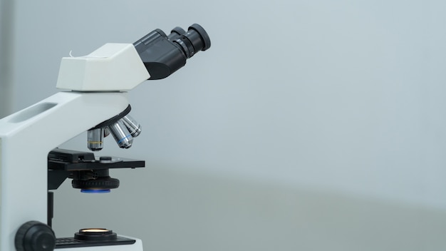 Primer plano y sesión de enfoque selectivo de un microscopio, tubos de ensayo médicos con líquido y otros equipos de laboratorio modernos en una sala de laboratorio. Educación foto de stock