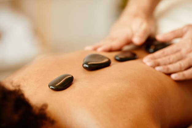 Primer plano de la sesión de terapia con piedras calientes en un relajante espacio de copia de spa