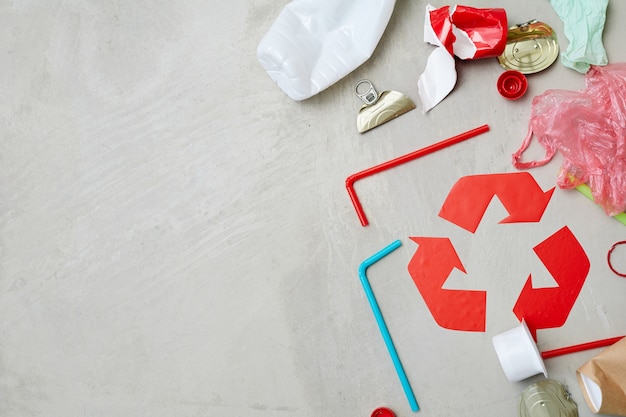 Primer plano del símbolo de reciclaje rojo con residuos aislado sobre fondo gris