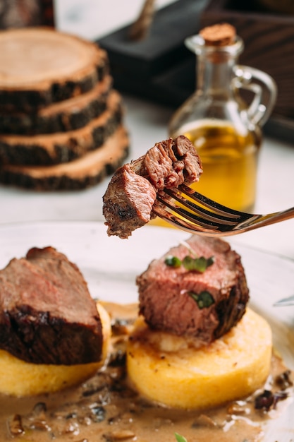 Primer plano sobre comer medallón de ternera asada en gachas de maíz con salsa de champiñones