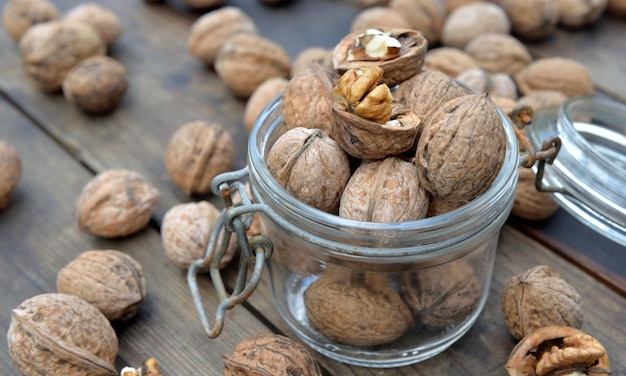 Primer plano sobre nueces en un frasco de vidrio, entre otros, sobre una mesa de madera