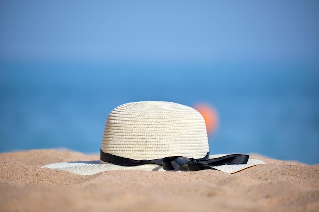 Primer plano de sombrero de paja amarillo en la playa de arena en la playa tropical en un cálido día de sol. Concepto de vacaciones de verano.