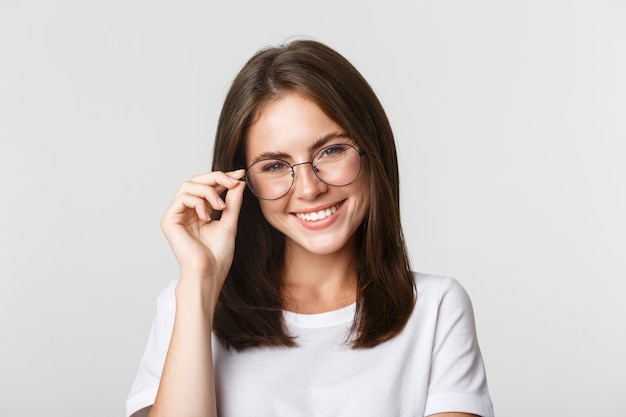 Primer plano de sonriente chica morena confiada, hermosa en gafas mirando feliz.