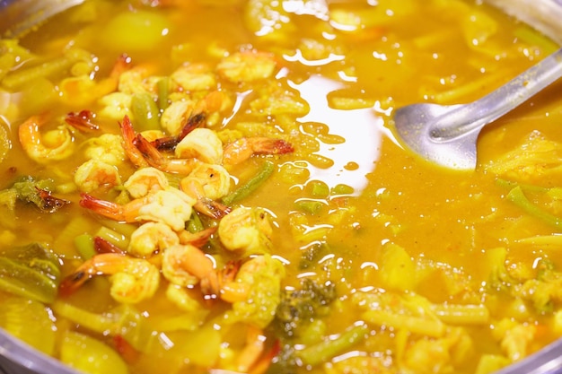 Primer plano de sopa agria con camarones y verduras en el mercado de comida callejera tailandesa