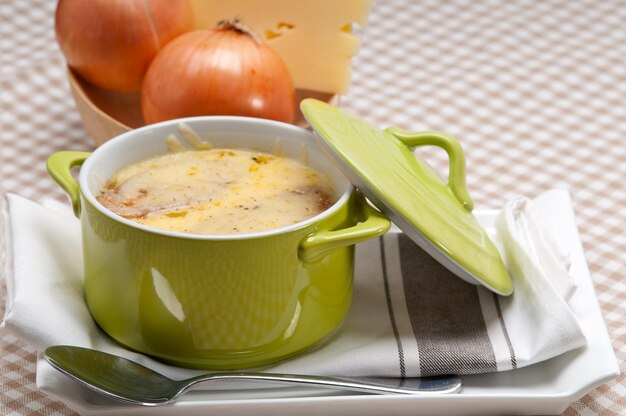 Foto primer plano de la sopa en el recipiente servida en la mesa contra las cebollas