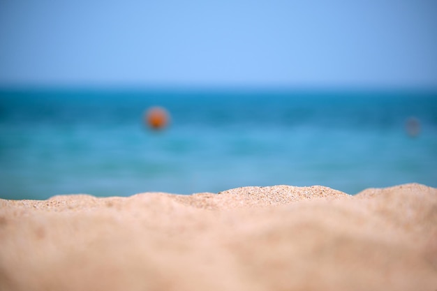 Primer plano de la superficie de arena amarilla limpia que cubre la playa junto al mar con agua de mar azul en el fondo Concepto de viajes y vacaciones