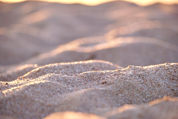 Primer plano de la superficie de arena amarilla limpia que cubre la playa junto al mar iluminada con la luz del atardecer Concepto de viajes y vacaciones