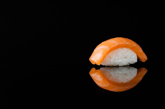 Primer plano de sushi con arroz sobre fondo negro con reflejo